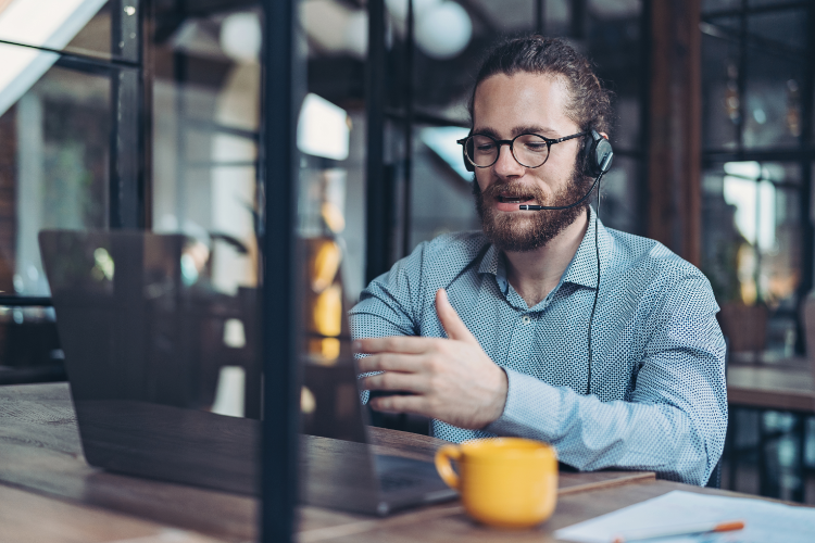Remote support agent using visual tools via laptop and headset for real-time customer assistance in a modern office setting.